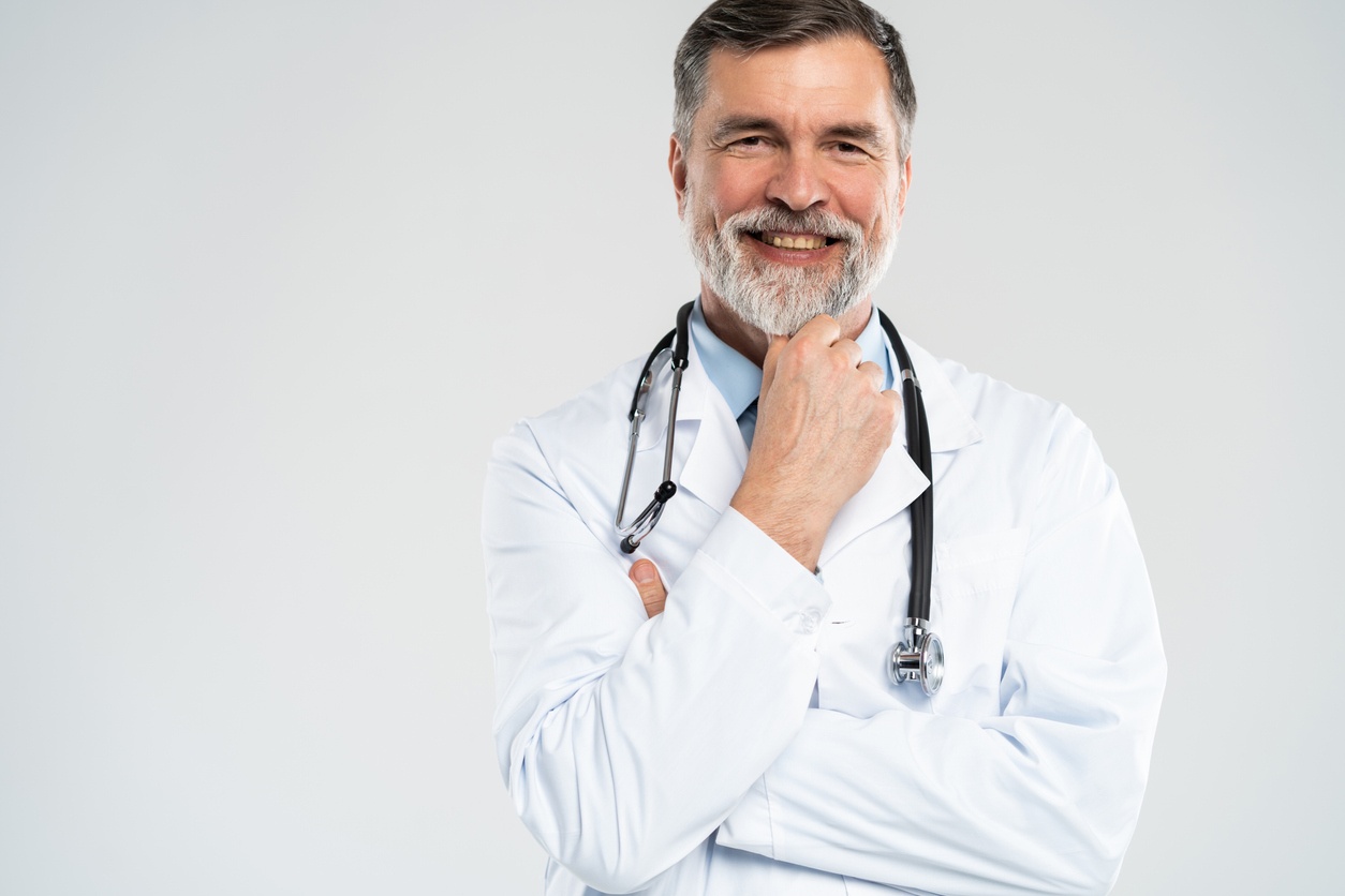 Cheerful mature doctor posing and smiling at camera, healthcare and medicine